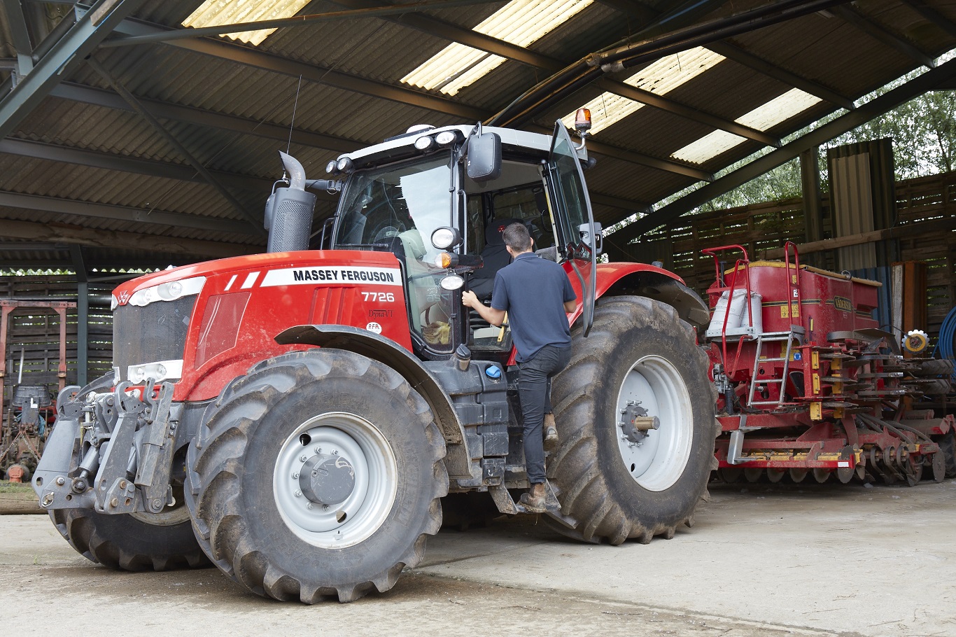 Farmer climbing into the cab of a red Massey Ferguson tractor