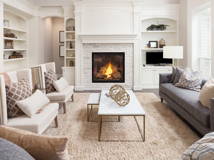 Modern living room in a high‑value home featuring a wide built‑in fireplace set into a stone wall.