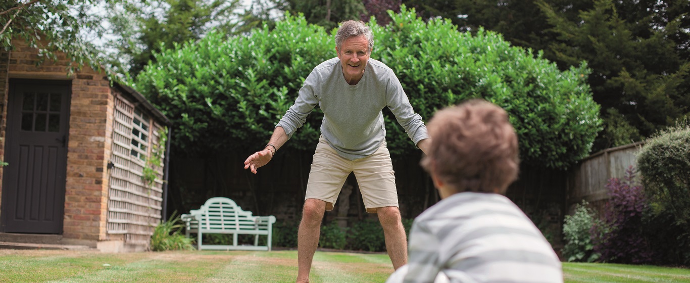 Grandfather and grandson playing football together in a garden
