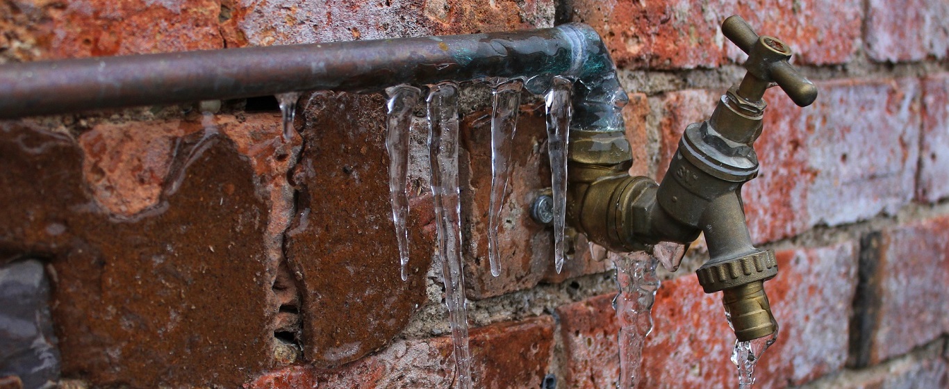 Outdoor tap with icicles forming on a frozen pipe