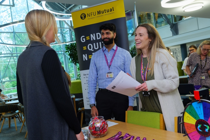 Gender equity network stand with attendees at the national inclusion week event.