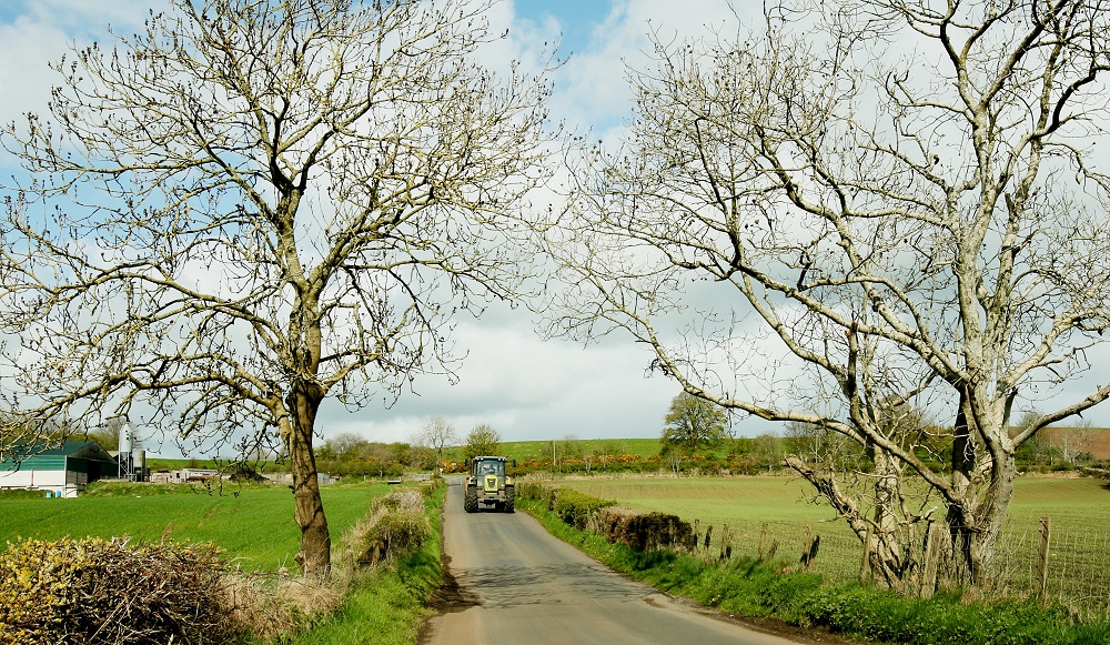 Tractor driving down a rural lane between fields