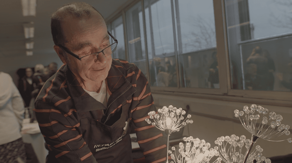 Person in apron looking at a decorative glass light fixture